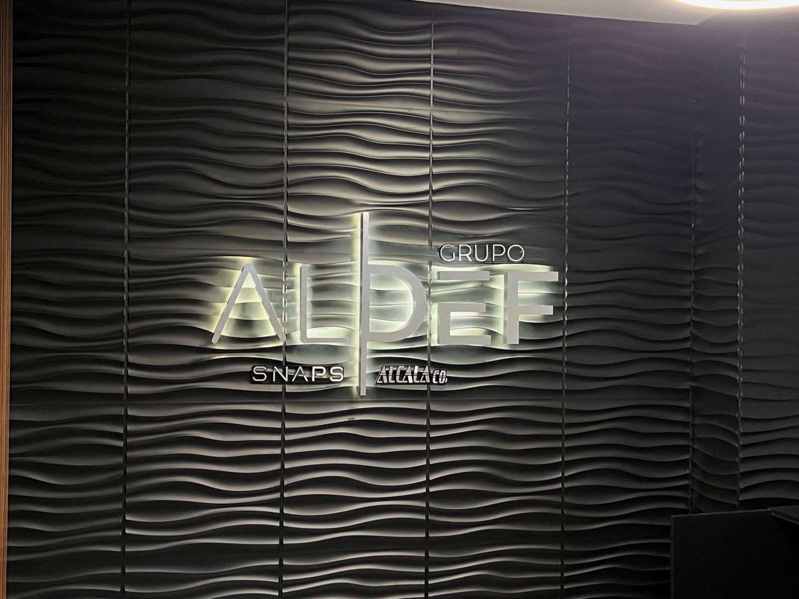 Anuncio luminoso GRUPO ALDEF encendido en la recepción, vista frontal