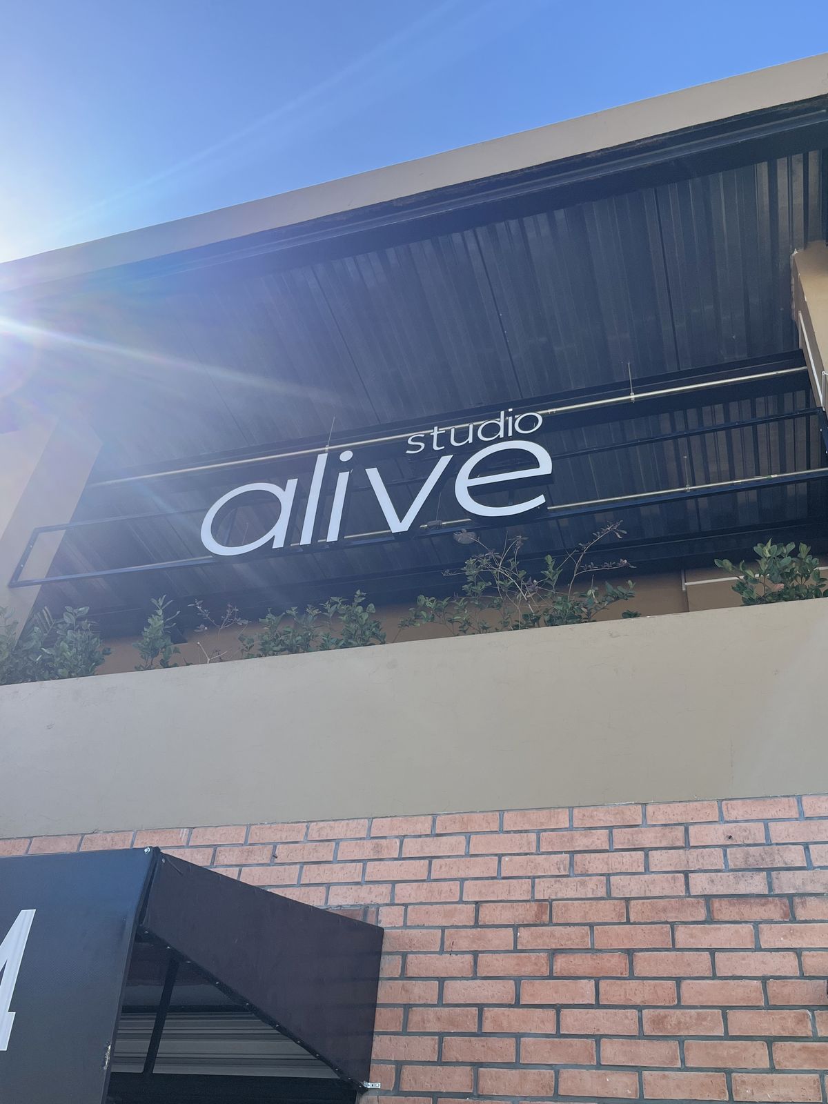 Fachada de Studio Alive con letras blancas sobre la estructura metálica del edificio