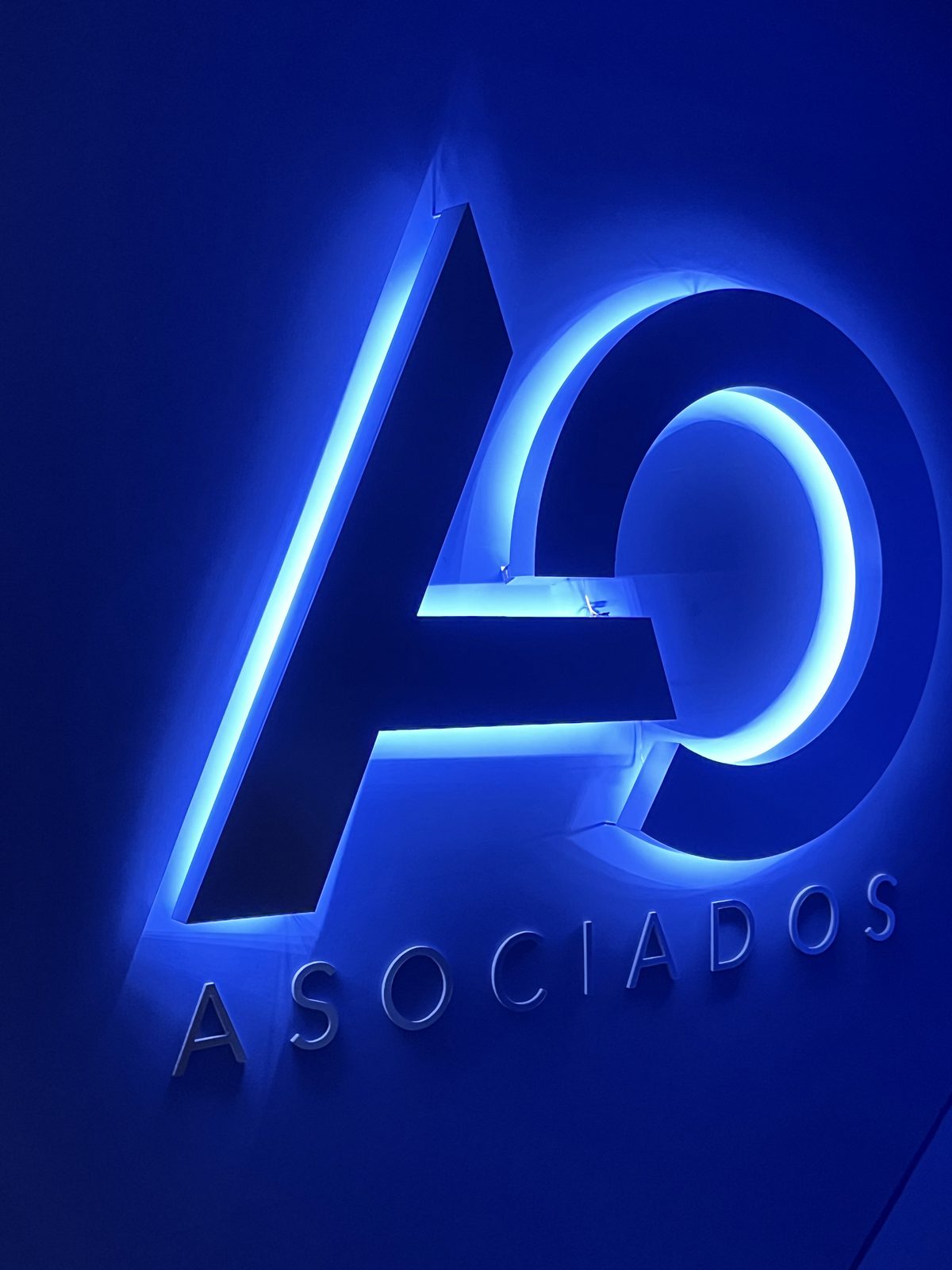 Anuncio luminoso de noche: letras AO en 3D con iluminación LED tipo halo y la palabra ASOCIADOS