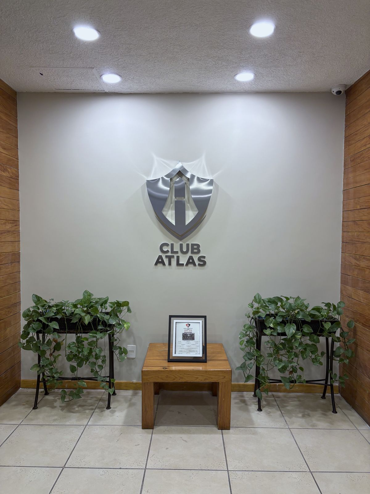 Vista general del recibidor con el escudo y el nombre Club Atlas en aluminio canteado sobre muro claro