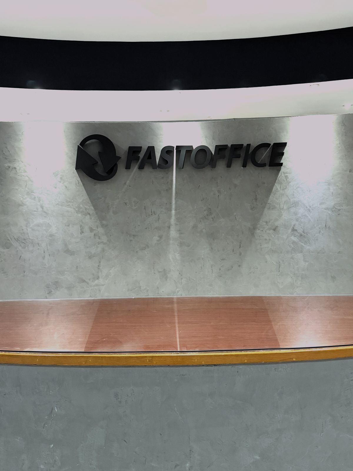 Vista general de la recepción con el anuncio FASTOFFICE en aluminio negro mate sobre el mostrador